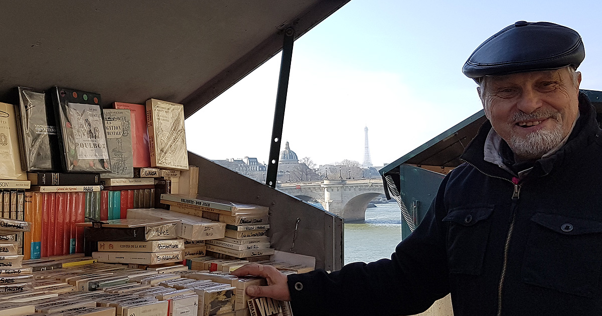 A Paris bouquiniste shows off his books with the Eiffel Tower in the background